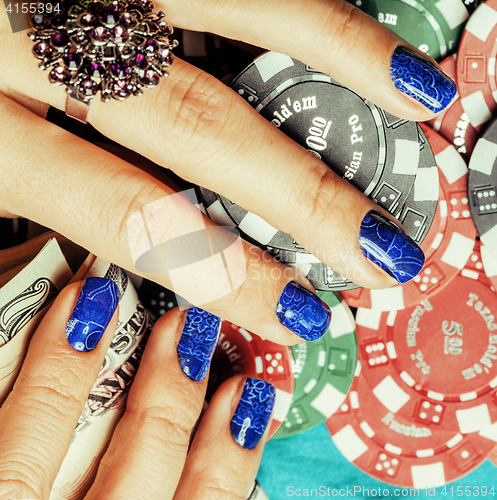 Image of hands of young caucasian woman with blue manicure at casino tabl