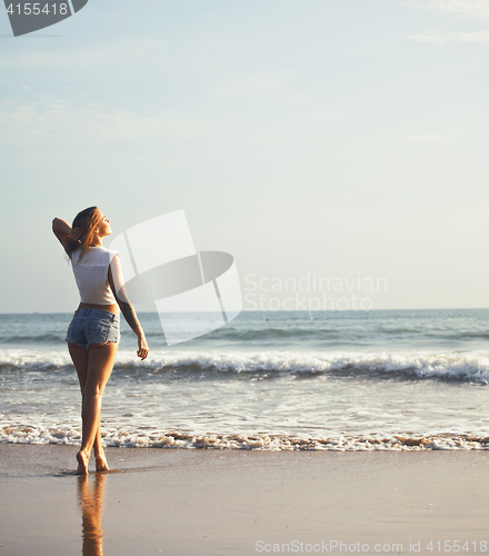 Image of real blonde girl along on seacost walking