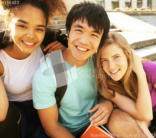 Image of cute group of teenages at the building of university with books huggings, back to school