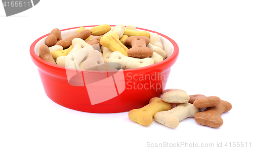 Image of Dry dog food in a red bowl, biscuits spilled beside