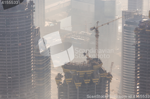 Image of Skyscrappers construction site with cranes on top of buildings.