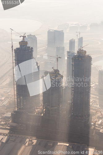 Image of Skyscrappers construction site with cranes on top of buildings.