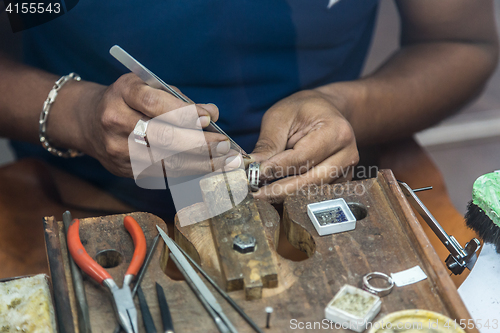 Image of Jeweler making handmade jewelry on vintage workbench.