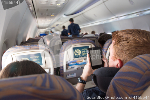 Image of Male passenger reading e-book on electronic reader on airplane.