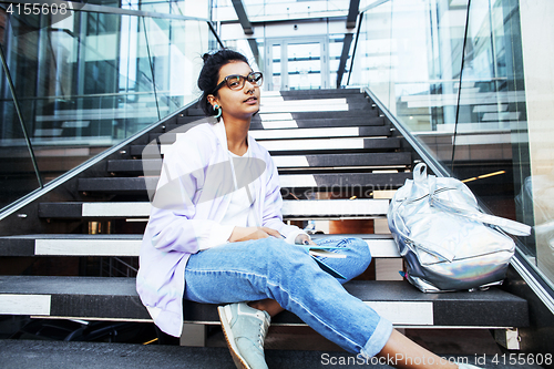 Image of young cute modern indian girl at university building sitting on 