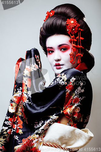 Image of young pretty geisha in black kimono among sakura, asian ethno