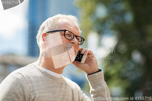 Image of happy senior man calling on smartphone in city