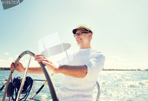 Image of senior man at helm on boat or yacht sailing in sea