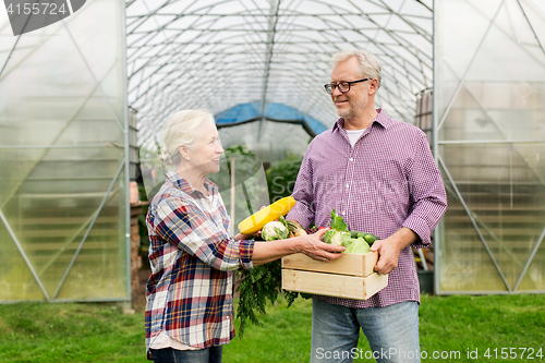 Image of senior couple with box of vegetables on farm