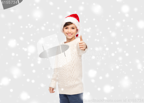 Image of smiling happy boy in santa hat showing thumbs up