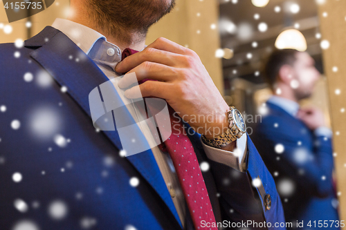 Image of close up of man trying tie on at clothing store