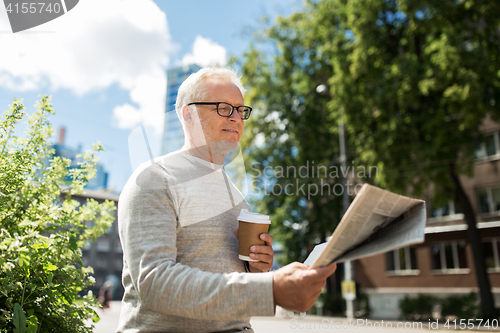 Image of senior man reading newspaper and drinking coffee