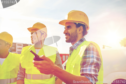 Image of happy male builders in vests with walkie talkie