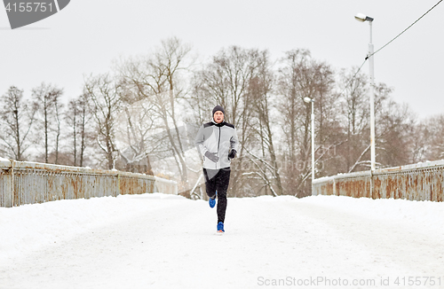 Image of man running along snow covered winter bridge road