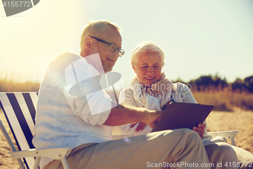 Image of happy senior couple with tablet pc on summer beach