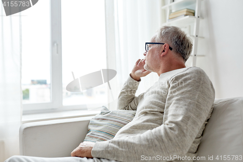 Image of senior man in glasses thinking at home