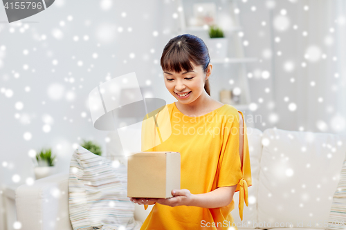 Image of happy asian young woman with parcel box at home