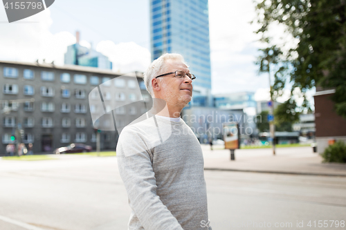 Image of senior man walking along summer city street