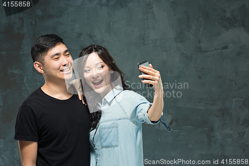 Image of Portrait of smiling Korean couple on a gray