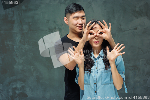 Image of Portrait of smiling Korean couple on a gray
