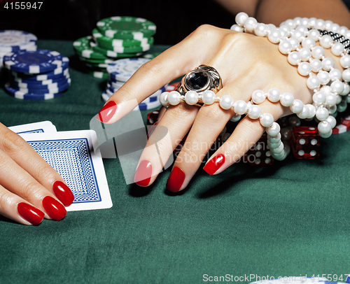 Image of hands of young caucasian woman with red manicure at casino table