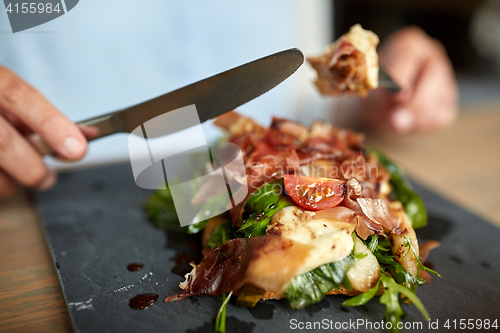 Image of woman eating prosciutto ham salad at restaurant