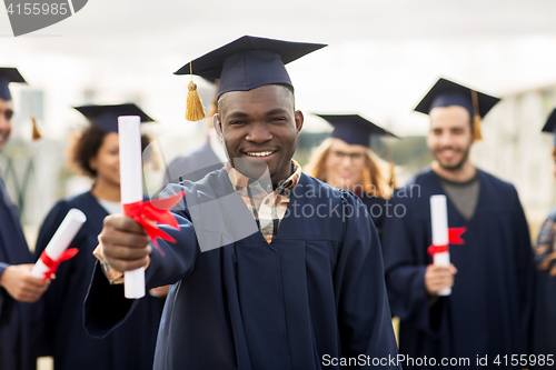 Image of happy students in mortar boards with diplomas