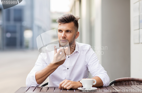 Image of man with coffee and smartphone at city cafe