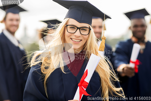 Image of happy students in mortar boards with diplomas