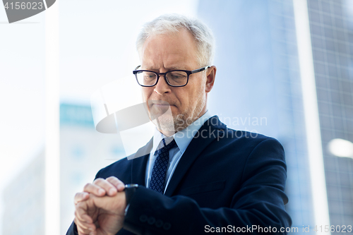 Image of senior businessman checking time on his wristwatch