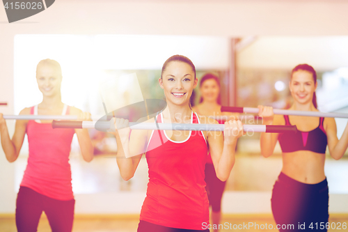 Image of group of smiling people working out with barbells