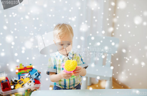 Image of happy little baby boy with ball clay at home