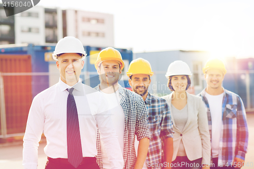 Image of group of smiling builders in hardhats outdoors