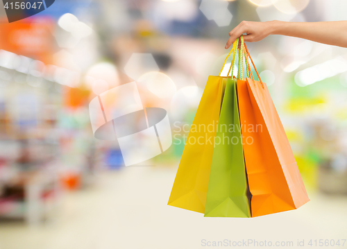 Image of hand with shopping bags over supermarket