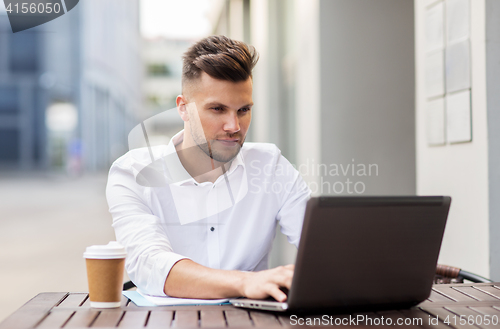 Image of man with laptop and coffee at city cafe