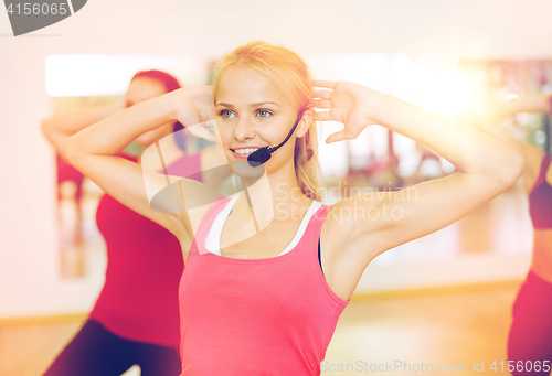 Image of group of smiling people exercising in the gym