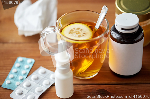 Image of cup of tea, drugs, honey and paper tissue on wood