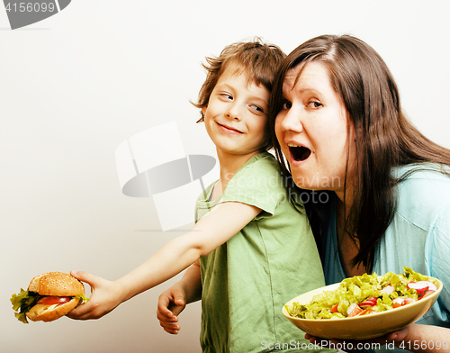 Image of fat woman holding salad and little cute boy with hamburger on white background