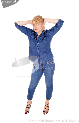 Image of Woman standing  with booths hands on head.