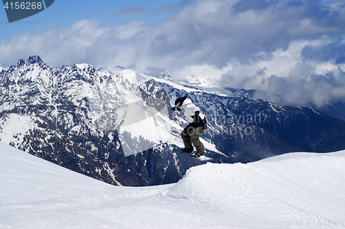 Image of Snowboarder jumping in snow park at ski resort on winter day