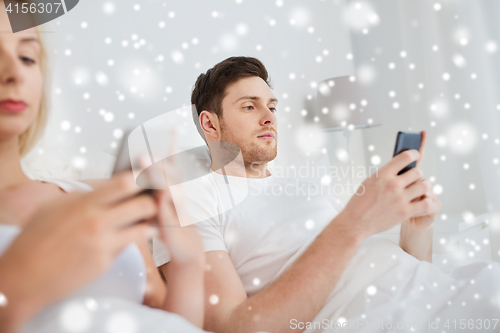 Image of couple with smartphones in bed