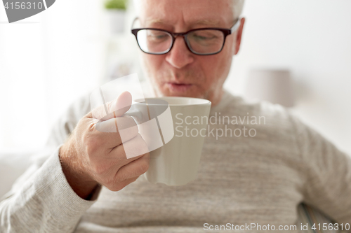 Image of happy senior man drinking tea or coffee at home