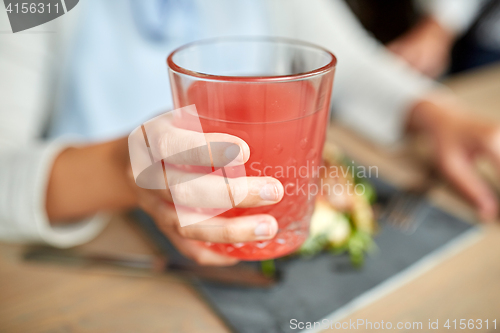 Image of hand with glass of juice at restaurant