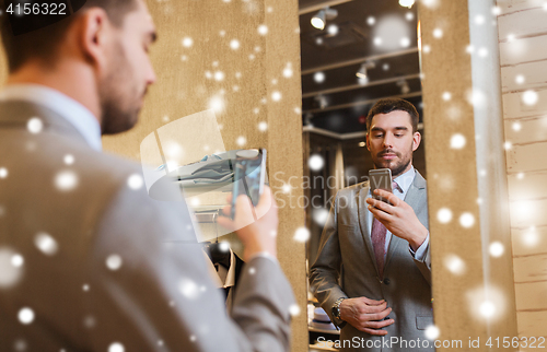Image of man in suit taking mirror selfie at clothing store