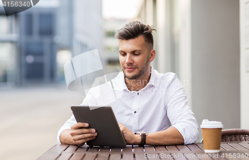 Image of man with tablet pc and coffee at city cafe