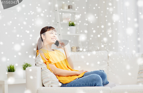 Image of happy asian woman calling on smartphone at home