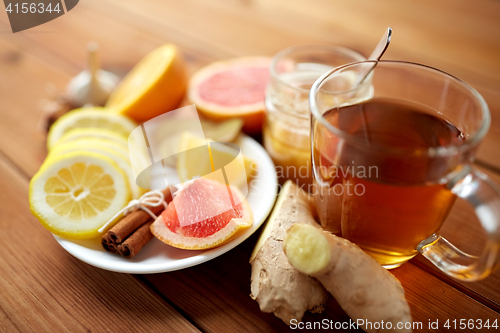 Image of ginger tea with honey, citrus and cinnamon on wood