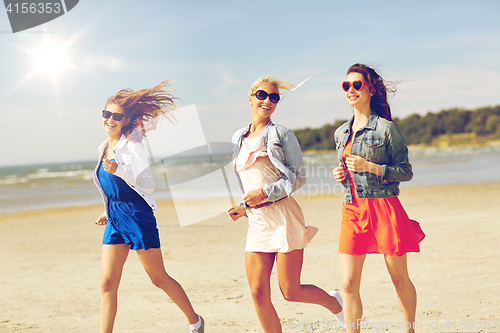 Image of group of smiling women in sunglasses on beach