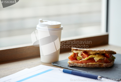 Image of salmon panini sandwich and cup of drink at cafe