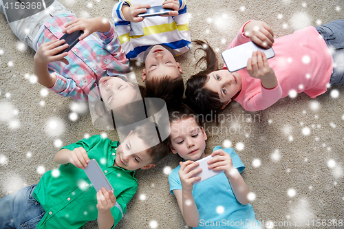 Image of children with smartphones lying on floor